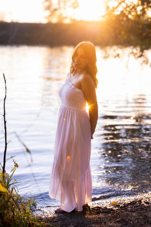 A series of silhouettes against a sunset at a lake shore, with a white dress glowing in the golden light.