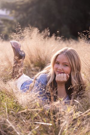 A person lies in golden sunlit grass with a dreamy expression in a series of casual outdoor portrait photos.
