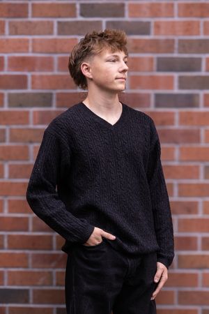 Person in black cable knit sweater poses against brick wall in multiple fashion photography shots.