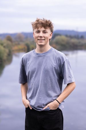 A casual portrait series against a waterfront background showing someone in a gray t-shirt and dark pants.