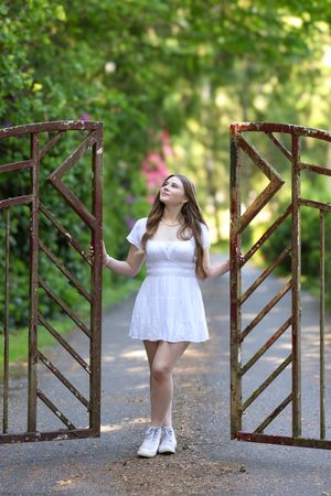 A sequence of photos shows a person in a white dress posing playfully against a rustic wooden gate in a garden setting.