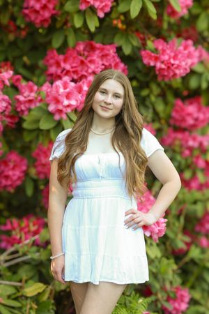 A springtime portrait session with pink azalea flowers creating a vibrant natural backdrop.
