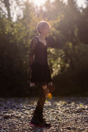 A silhouetted figure walks on rocky ground at sunset, creating a moody atmospheric scene.