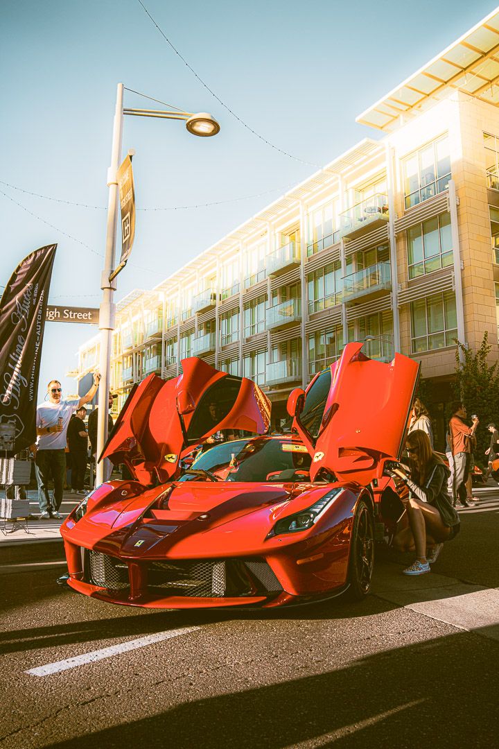 Four sequential photos show a red Ferrari LaFerrari with its distinctive scissor doors open in front of a modern building.