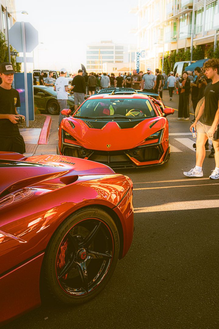 Row of red McLaren supercars showcased at an outdoor car meet.