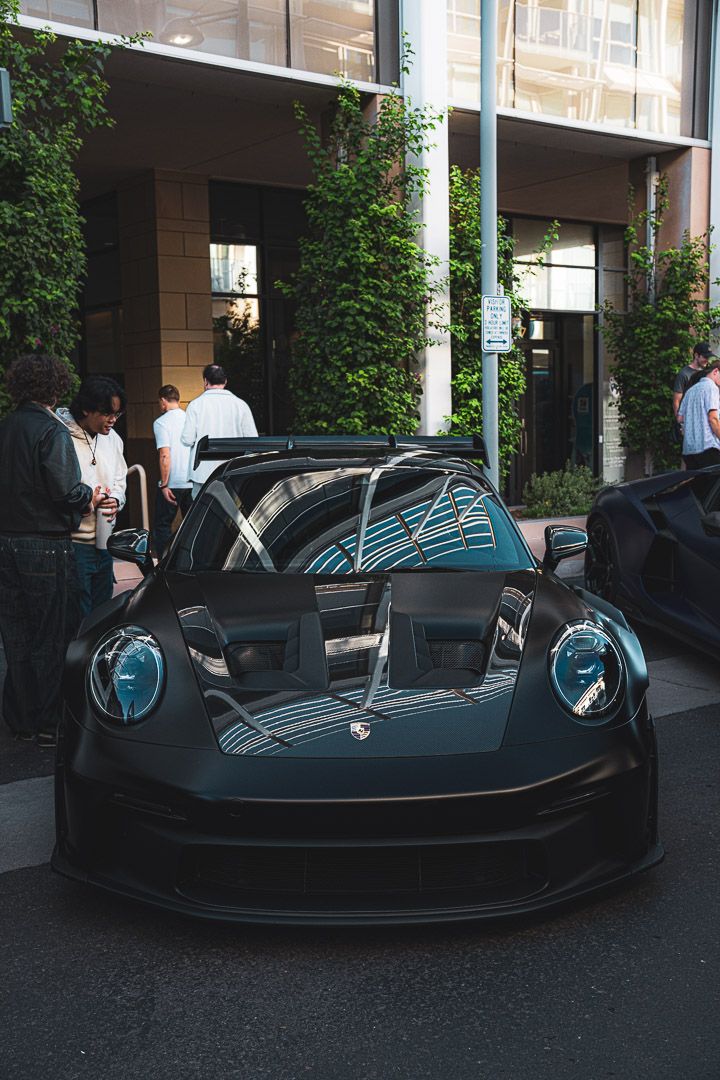 Sleek black McLaren sports car with blue accents displayed under building overhang.
