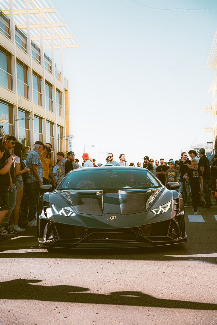 Front view of a black Lamborghini Huracan surrounded by car enthusiasts.