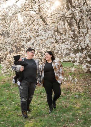 A couple walks through a blooming cherry blossom orchard during springtime, creating a romantic scene.