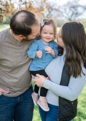 A family shares tender moments together outdoors during an autumn photo session in a field.