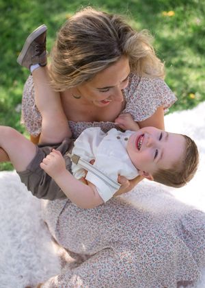 A tender moment shared between two people lying on a blanket outdoors on a sunny day.