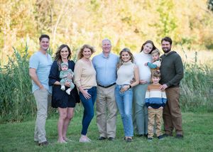 A group stands together in an outdoor field during golden hour wearing coordinated casual outfits in blue and neutral tones.