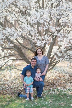 A family sits together under a blooming cherry blossom tree during spring.
