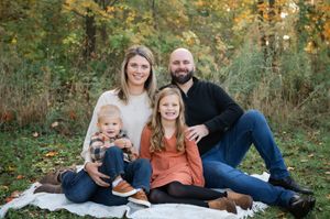Family portrait session in a scenic autumn forest with warm natural lighting and casual outfits.