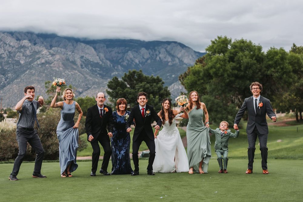 Wedding party celebrates on a scenic golf course with mountain views in the background.