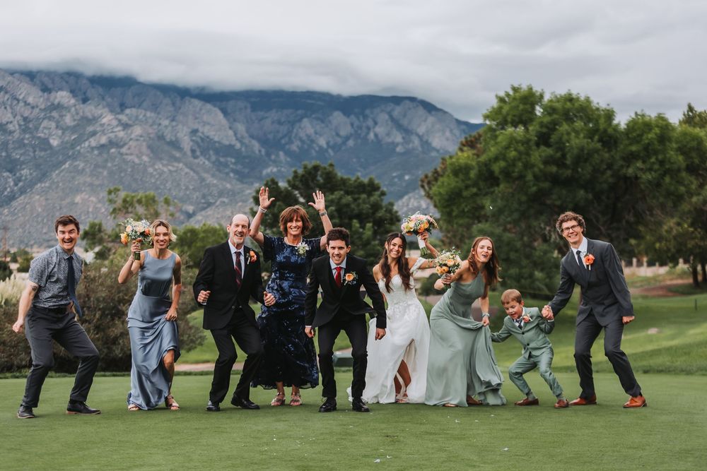 Wedding guests enjoy outdoor games and activities on a grassy lawn with scenic mountain views in the background.