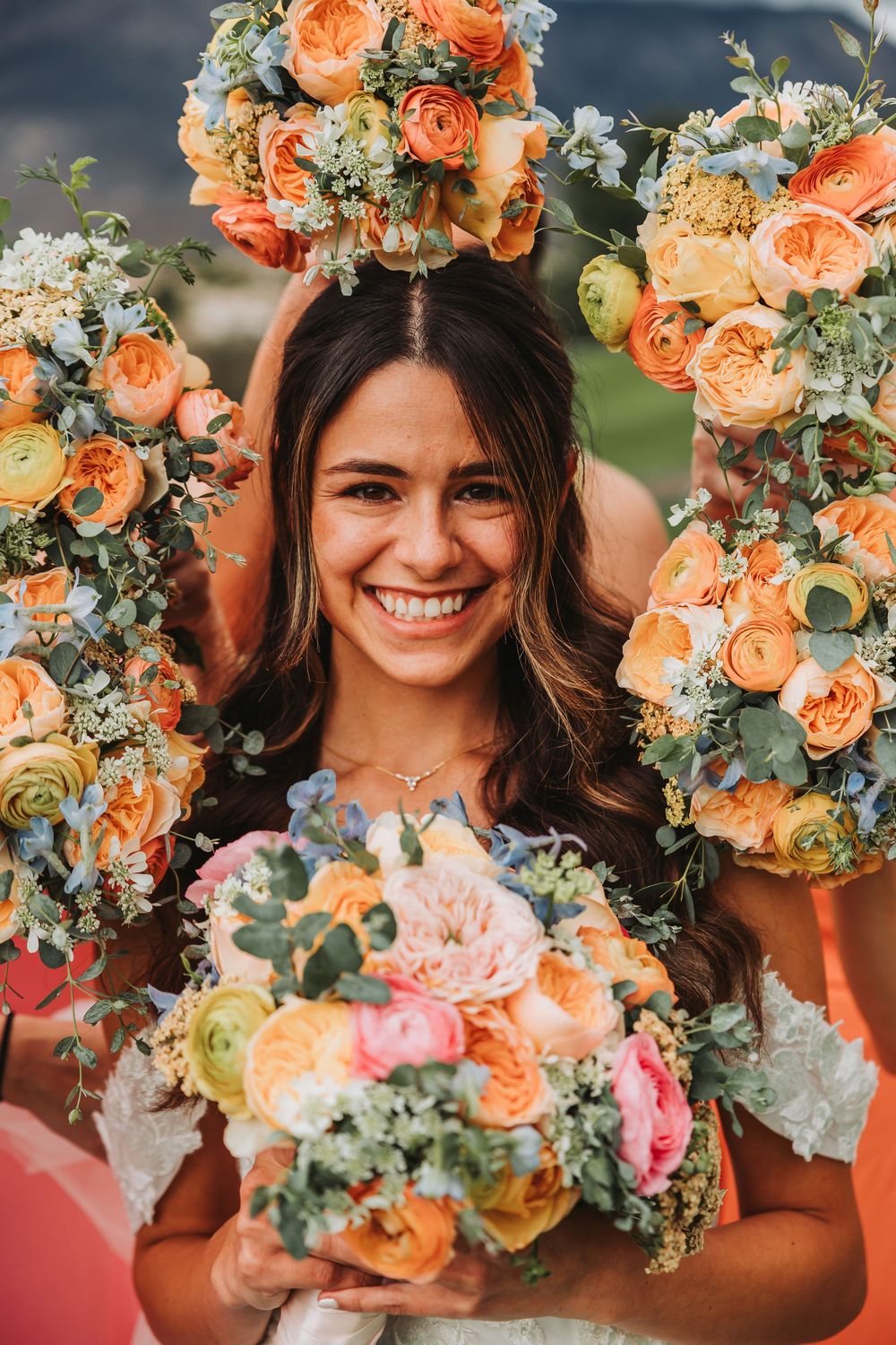 Beautiful peach and coral floral arrangements with roses, ranunculus and eucalyptus in soft natural lighting.