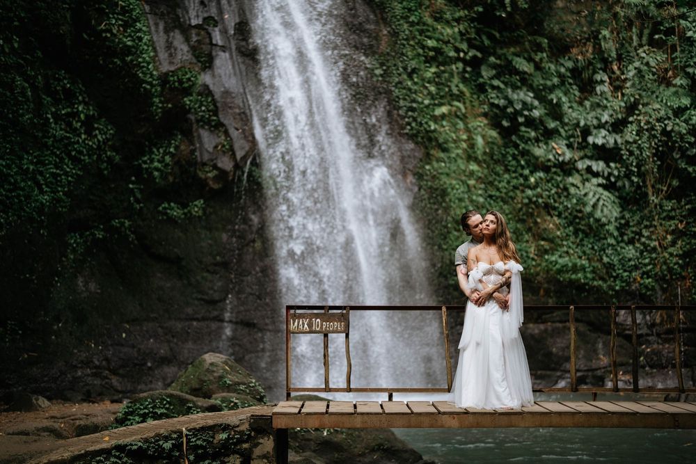 Romantic post wedding photography services at Ulu Petanu Waterfall Bali with lush jungle and waterfall backdrop.