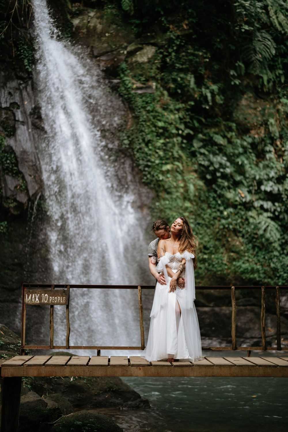 Romantic post wedding photography services at Ulu Petanu Waterfall Bali with lush jungle and waterfall backdrop.