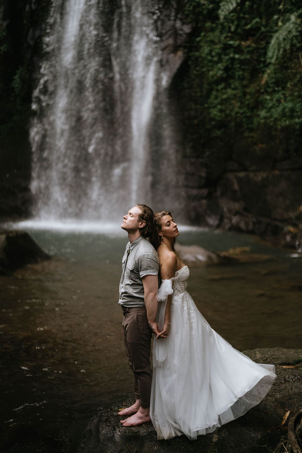 Romantic post wedding photography services at Ulu Petanu Waterfall Bali with lush jungle and waterfall backdrop.
