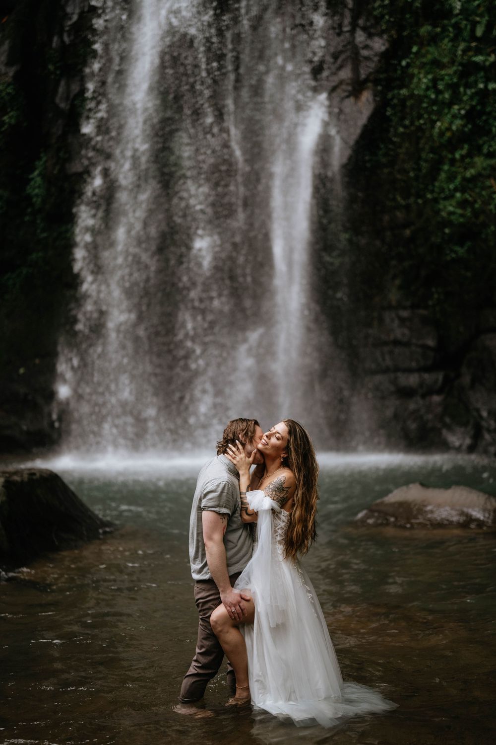 Romantic post wedding photography services at Ulu Petanu Waterfall Bali with lush jungle and waterfall backdrop.