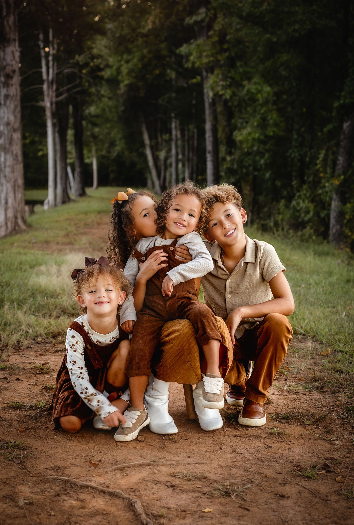 Four adorable sibling snuggled together in matching brown outfits against an early fall sitting during Charlottesville family session.