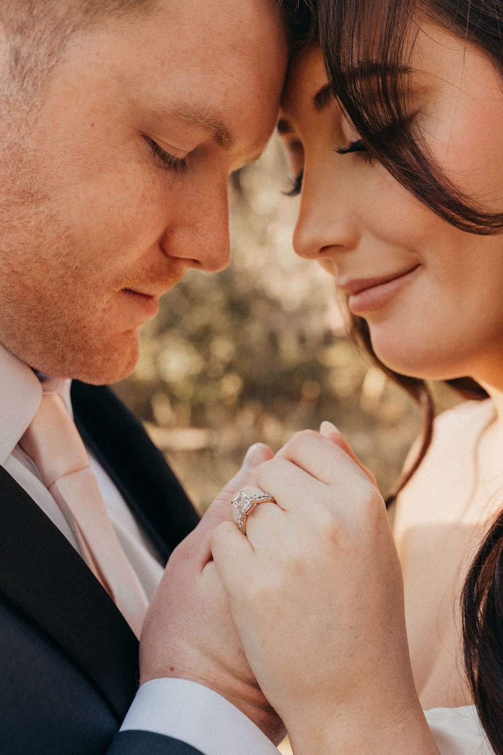 A close-up intimate moment of a couple sharing a tender embrace while showing off an engagement ring.
