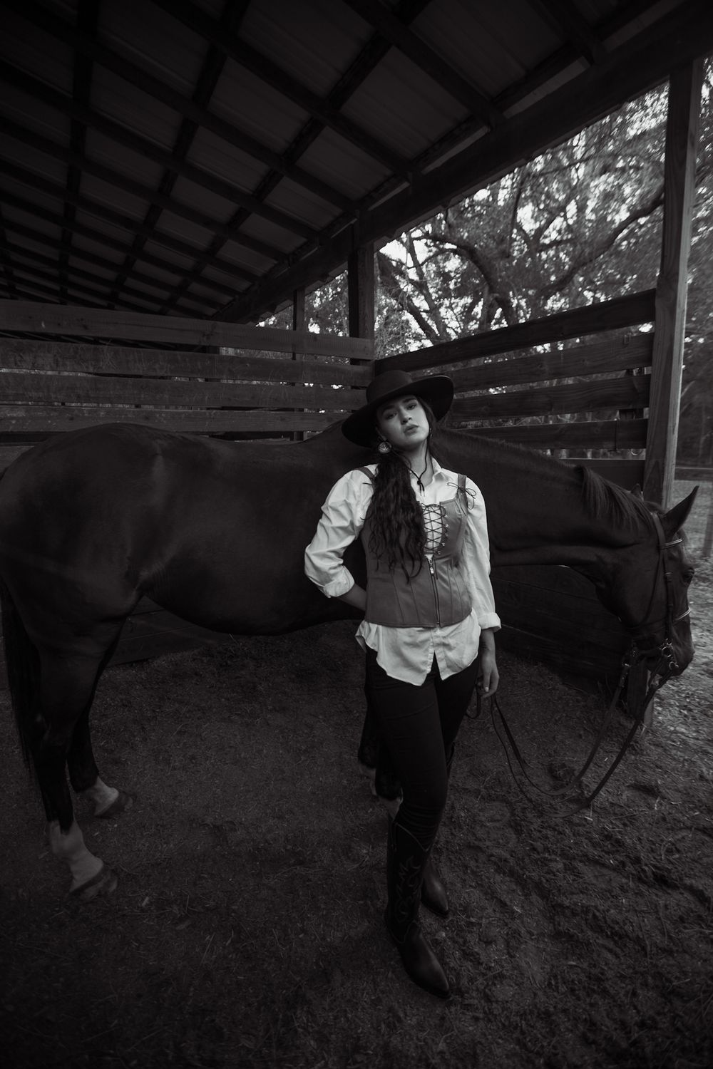 Dramatic black and white portrait with horse in rustic stable setting.