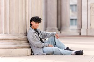 Person in gray loungewear relaxes while laying against stone pillars in an urban setting.