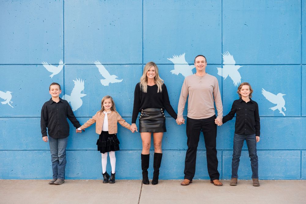 People sitting on a bench against a bright blue wall decorated with white bird silhouettes.
