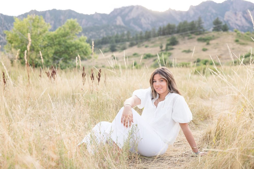 A romantic photoshoot in a golden field with mountains in the background during sunset.