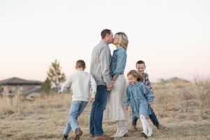 Family walking together in a field at sunset wearing coordinated denim and white outfits.