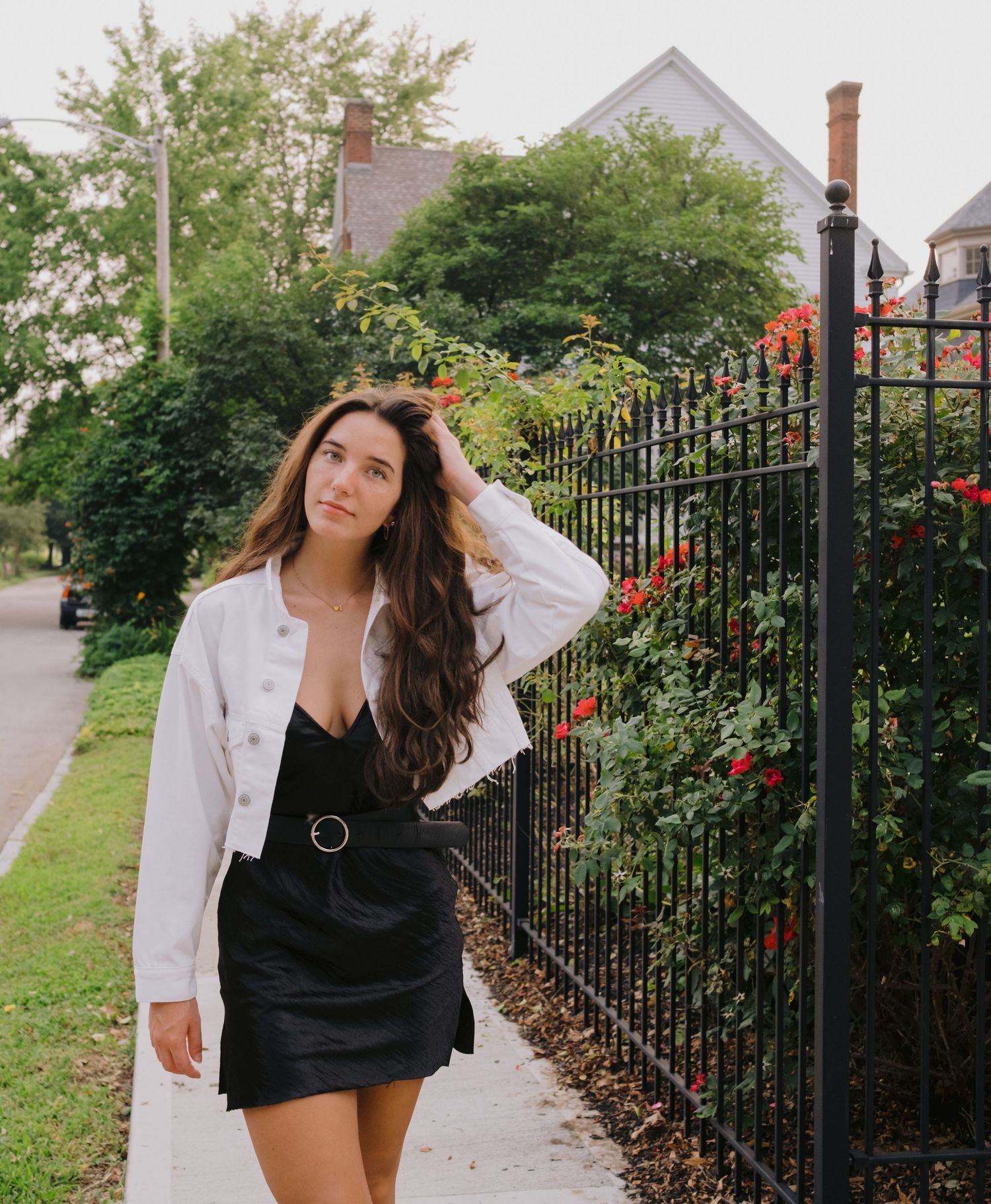 Summer fashion shoot by a wrought iron fence with blooming flowers and greenery.