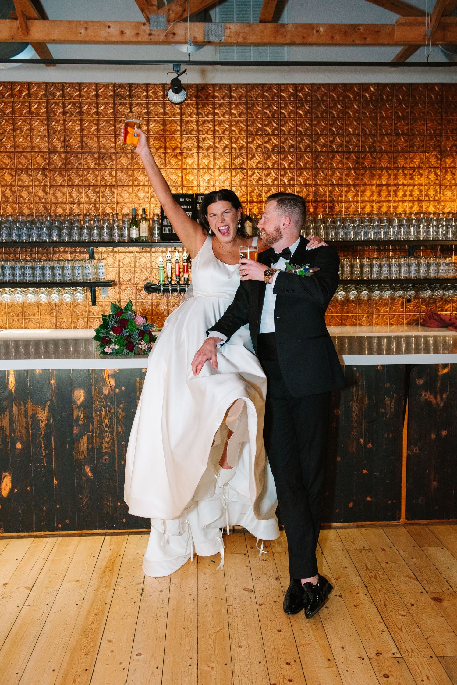 Wedding celebration in rustic venue with decorative copper wall and wooden beams.