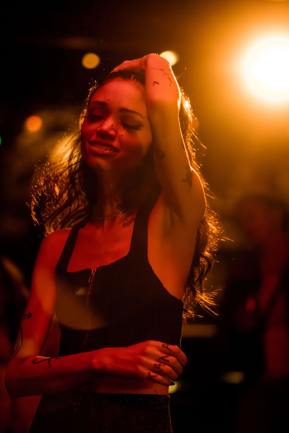 A figure dances in warm orange lighting at a nightclub, creating a moody and atmospheric scene.