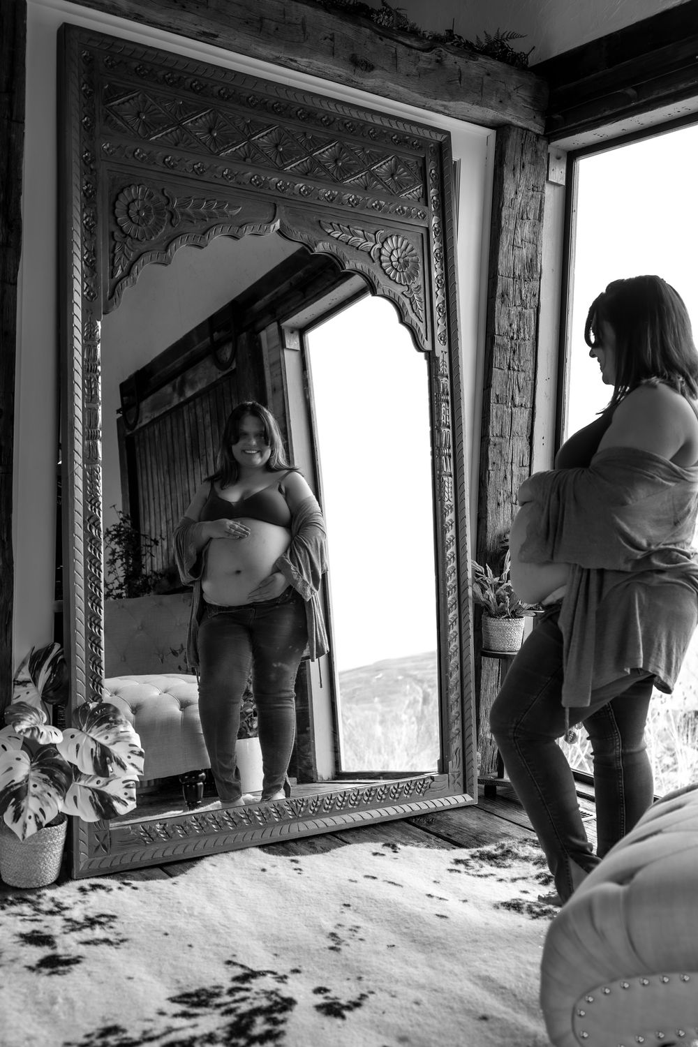 Black and white reflection in an ornate mirror with decorative carved frame in an interior setting.