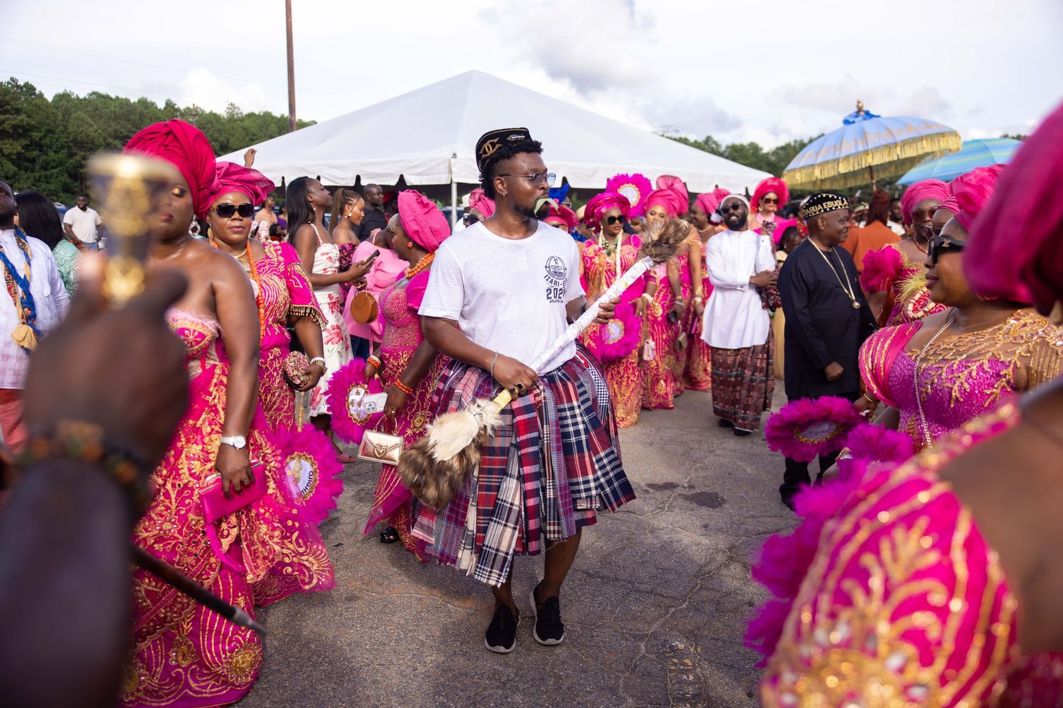 Crowd in pink and red traditional outfits participating in a cultural festival or celebration.