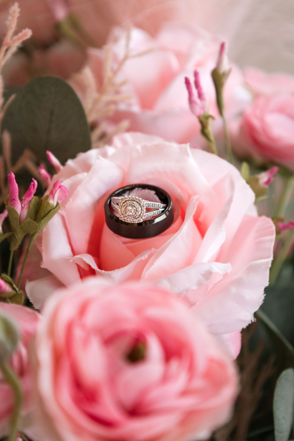 Diamond engagement ring nestled in pink roses with soft focus floral background.