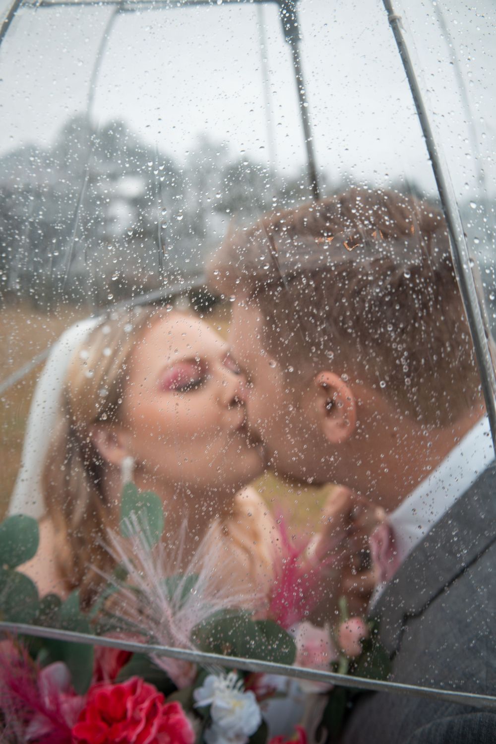 A romantic kiss under a clear umbrella in the rain.