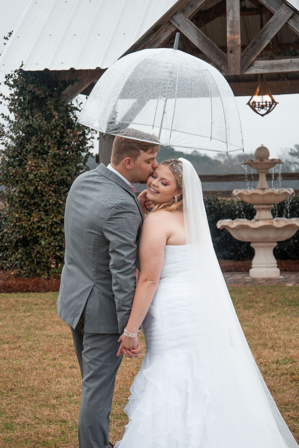 A tender moment shared under a white umbrella on wedding day.