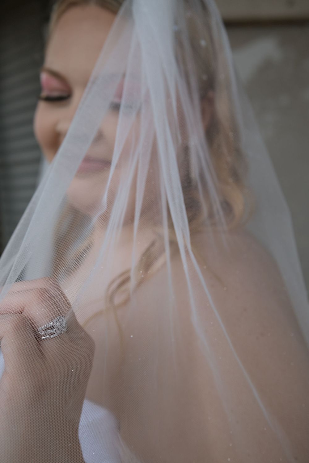 Close-up details of a delicate white wedding veil with soft lighting and romantic ambiance.