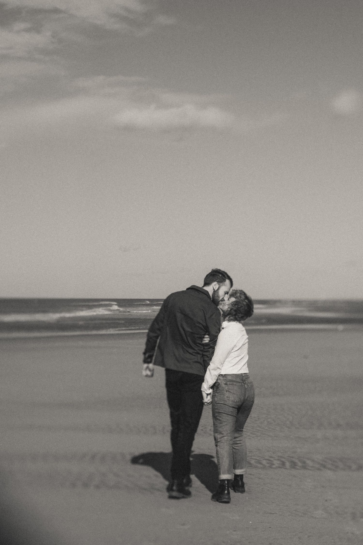 A couple walking hand in hand along Nederzandt Beach with waves in the background.