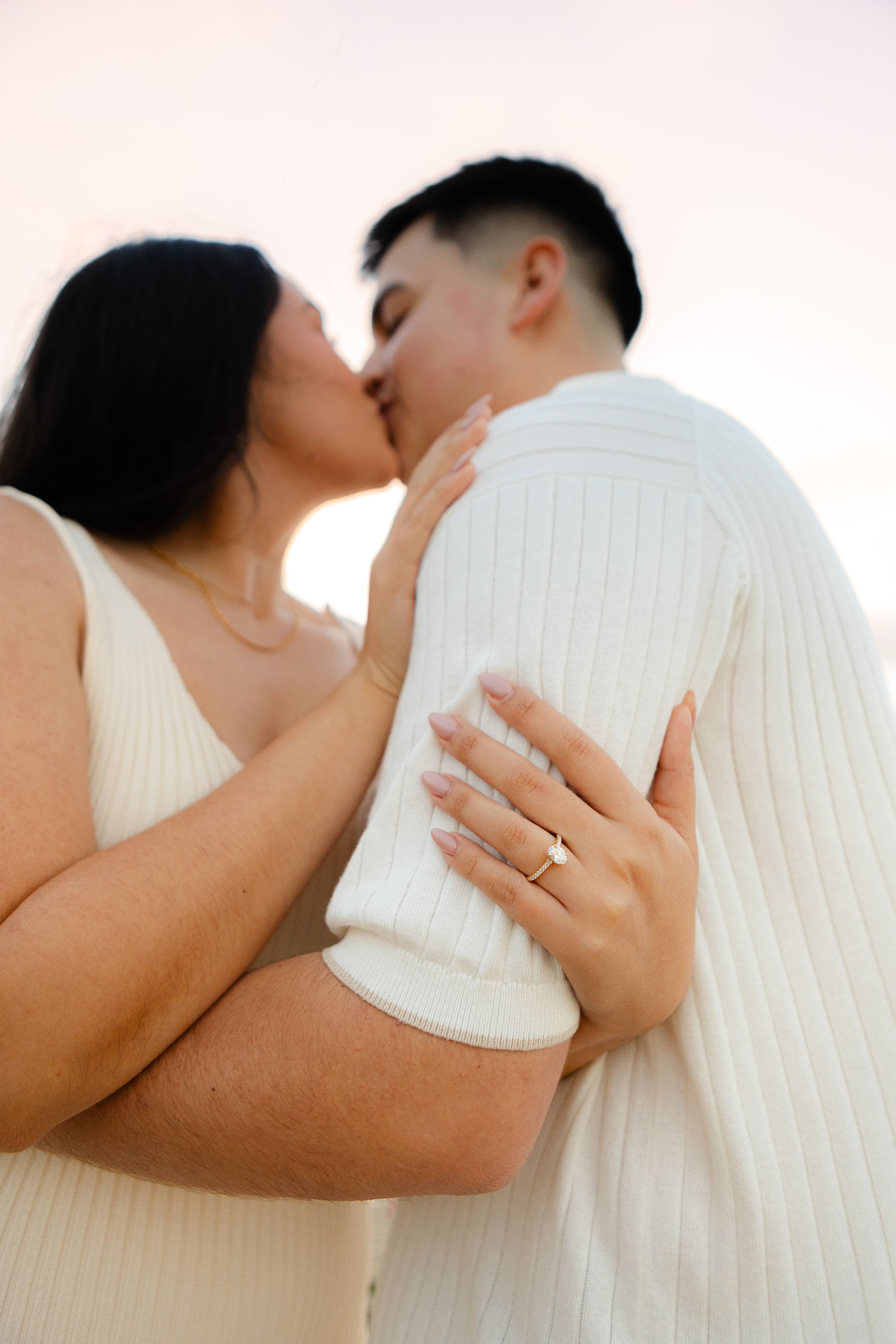 Close-up romantic moment with engagement ring display at sunset.