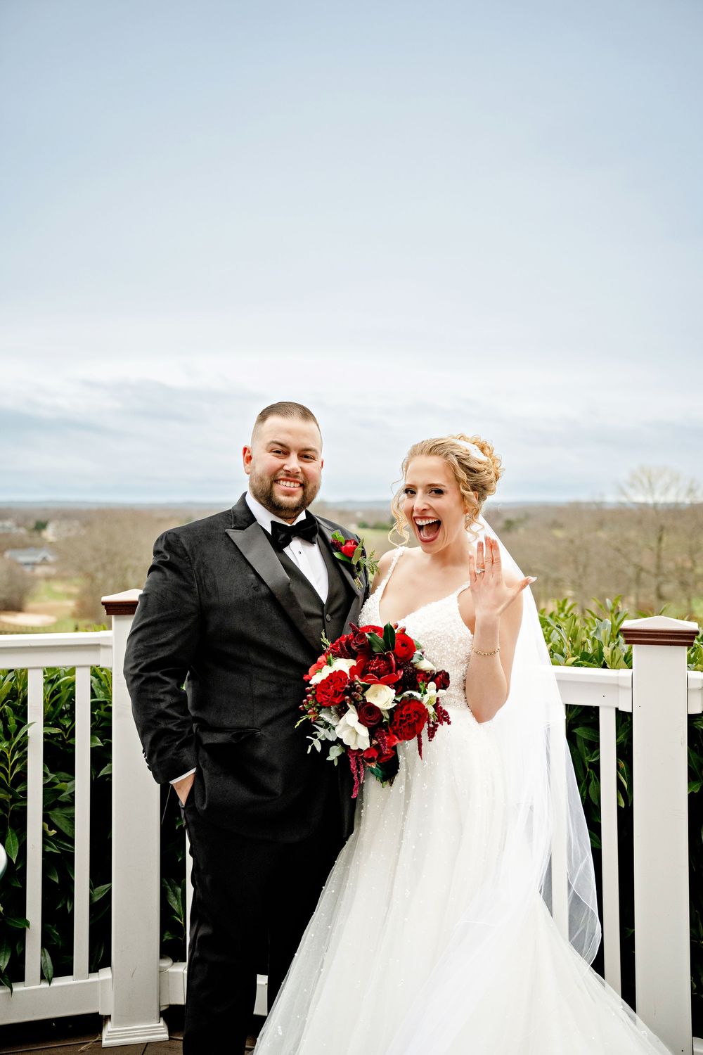 A happy couple shares joyful moments on their wedding day, wearing traditional black and white attire on an outdoor deck.