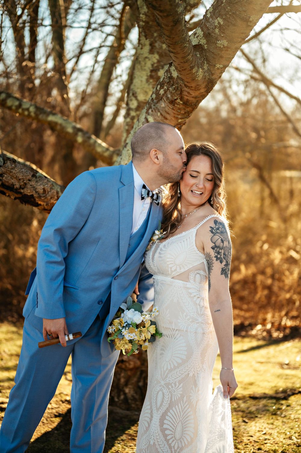 Intimate golden hour wedding portrait under branching trees in autumn.