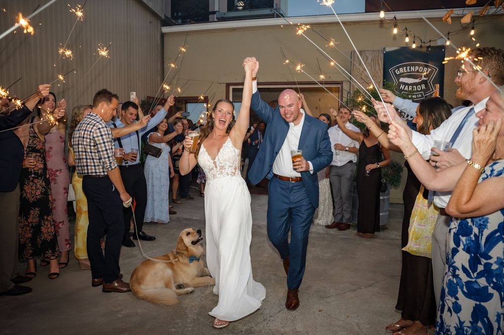 Wedding guests dancing and celebrating on the dance floor under warm string lights at an indoor reception.