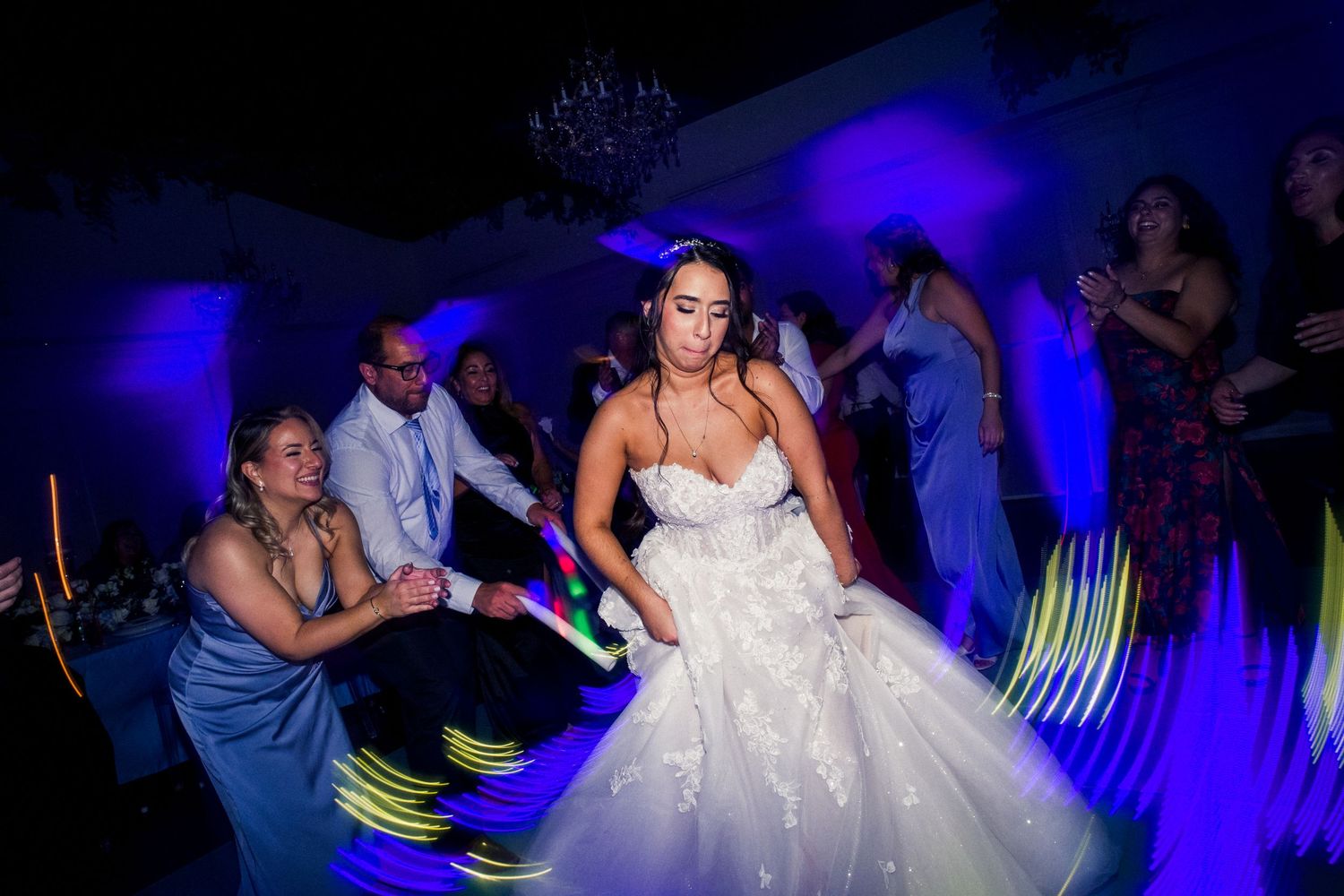 A bride dancing at her reception with blue uplighting and light trails creating a dynamic scene.
