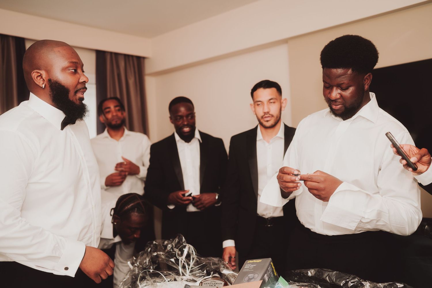 Wedding party members in white dress shirts gather around a table during festivities.