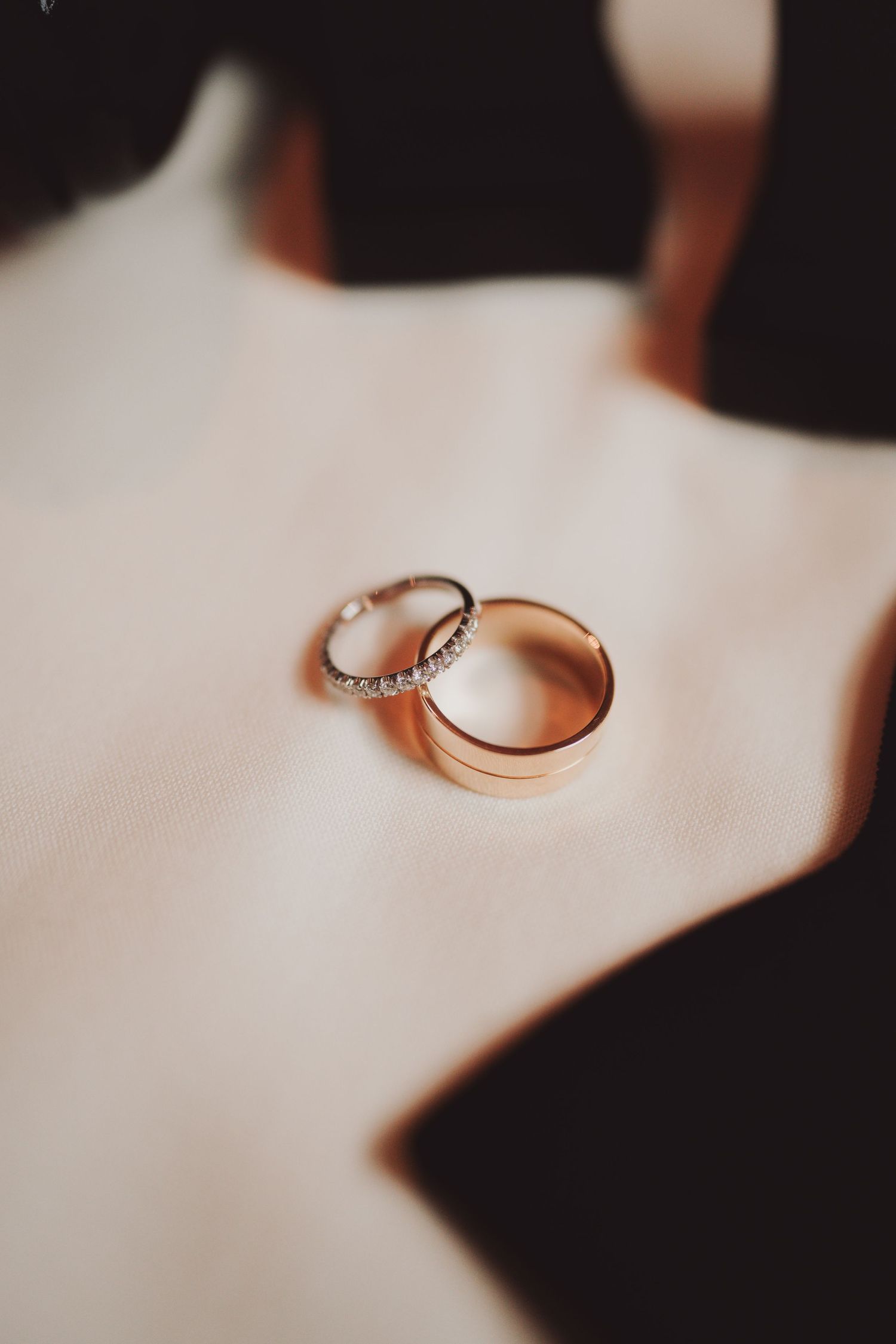 Wedding rings displayed on white fabric with one band featuring diamonds.