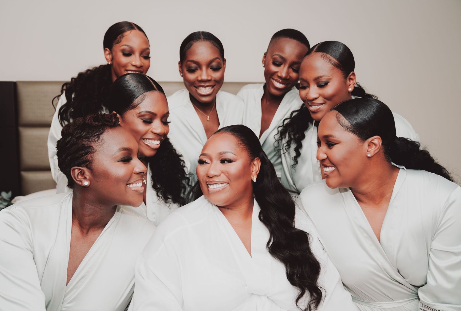 Group wearing matching white robes posing together in pre-wedding preparation.