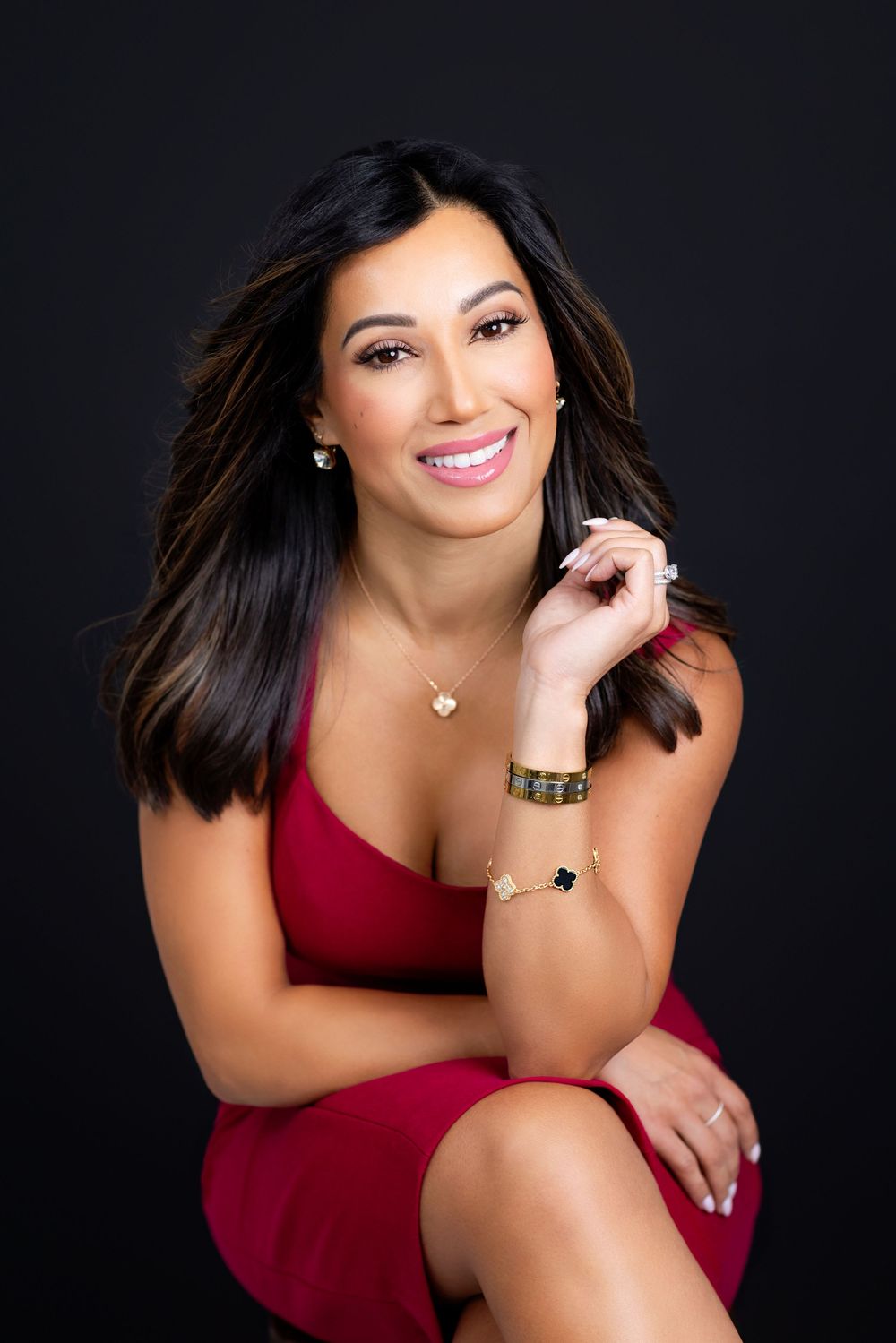 Woman in red dress poses confidently against dark background in elegant portrait series.